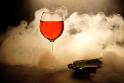 Close-up of wineglass on table amidst smoke