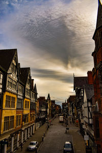 City street amidst buildings against sky during sunset