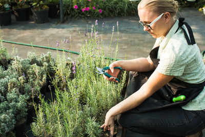 Woman using mobile phone while standing on plants