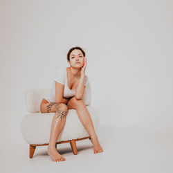 Portrait of young woman sitting against white background