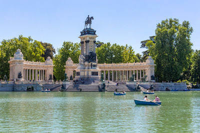 People rowing boats on a lake at retiro park in madrid, spain