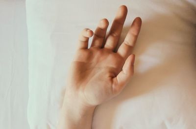 Close-up of person hand on bed