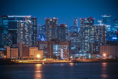 Illuminated buildings in city against sky at night