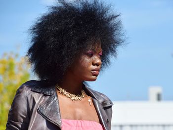 Young woman looking away against sky