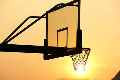 Low angle view of basketball hoop against sky at sunset