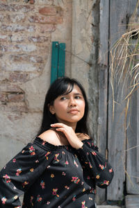 Young woman looking away standing against wall