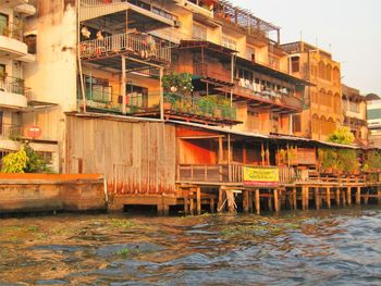 Houses by river against buildings in city