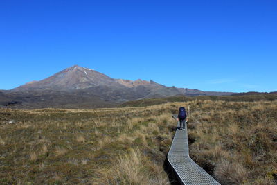 Rear view of man on mountain against clear blue sky