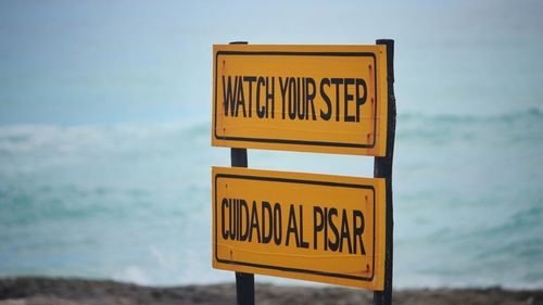 Information sign on beach against sky