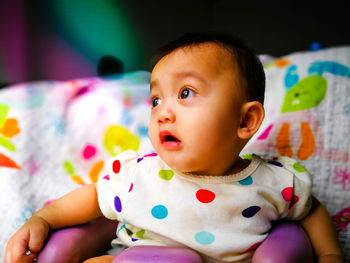 Close-up of cute baby girl drooling while sitting on chair at home