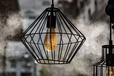 Low angle view of illuminated light bulb hanging on street