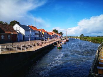 Buildings by river against sky