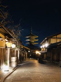 Illuminated bridge amidst buildings against sky at night