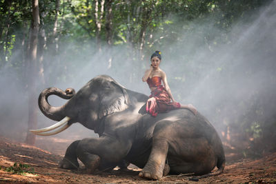 Full length of young woman sitting on land