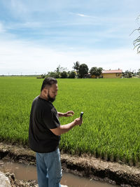 Rear view of man standing on field against sky