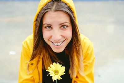 Portrait of young woman standing by flowering plant