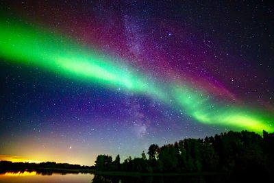 Low angle view of aurora borealis over lake at night