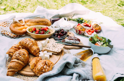 Picnic in the field with berries, juice, cheese, sausage and sweet croissants