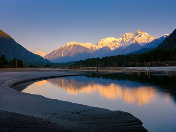 Scenic view of lake by mountains against sky during sunset