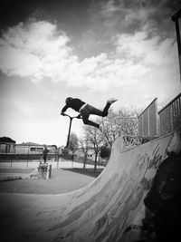 Low angle view of person jumping on road against sky