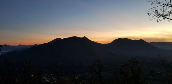 Scenic view of silhouette mountains against orange sky