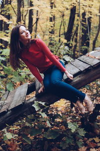 Young woman sitting on damaged floorboard in forest