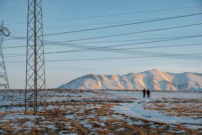 Rear view of men standing on snow covered landscape