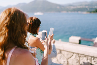 Rear view of woman photographing sea