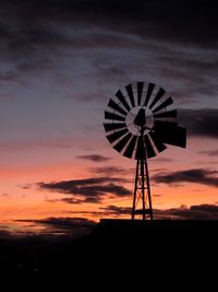 Silhouette of windmill on field against sky during sunset