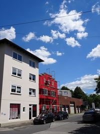 Cars on road by buildings against sky