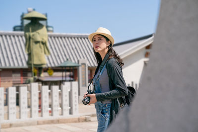 Woman wearing hat standing against sky