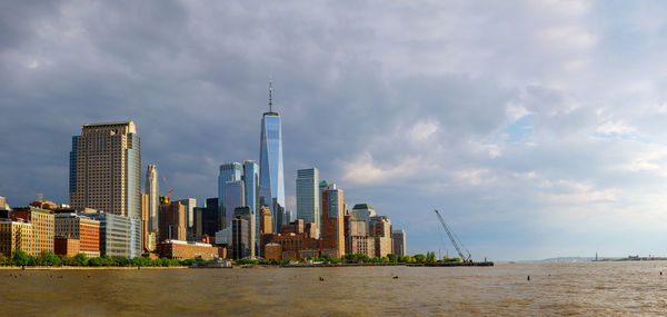 City at waterfront against cloudy sky