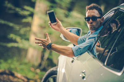 Man gesturing holding smart phone in car