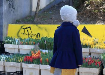 Rear view of girl standing at flower shop