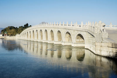 Arch bridge over lake against sky