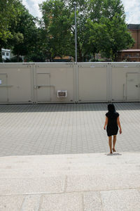 Rear view of woman standing by trees