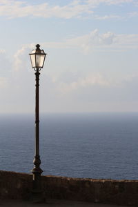 Street light by sea against sky