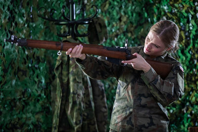 In the barracks, a lady soldier measures with a self-repeating rifle.