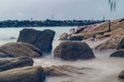 Scenic view of rocks on beach against sky