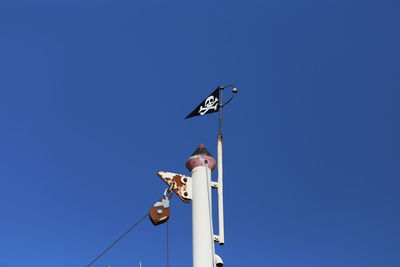 Low angle view of bird on pole against clear blue sky