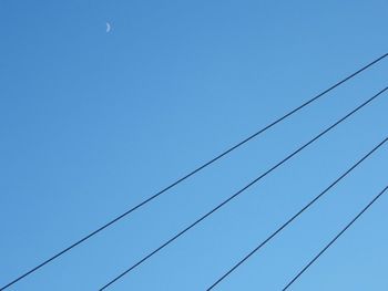 Low angle view of power lines against clear blue sky