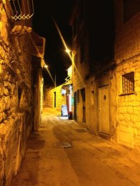 Narrow empty road along buildings at night