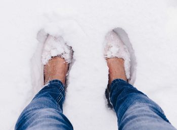 Low section of man standing on snow covered field