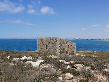 Built structure on beach by sea against sky