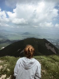 Rear view of woman on mountain against cloudy sky