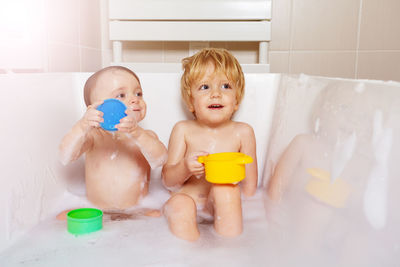 Portrait of cute baby boy washing hands in bathtub