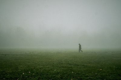 Man walking on field in foggy weather