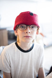 Close-up portrait of boy wearing eyeglasses and knit hat while sitting at home