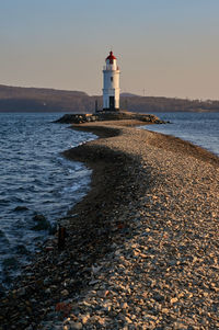 Lighthouse by sea against sky