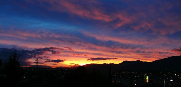 Silhouette cityscape against sky at sunset